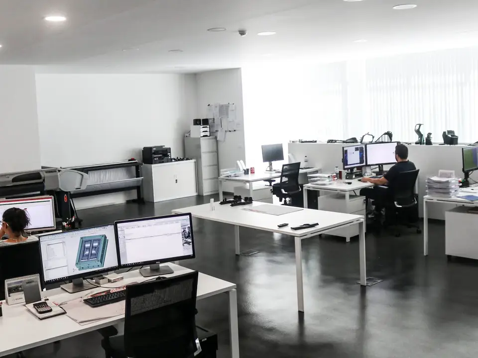 Gabinete de projeto da Jorge Cadete: postos de trabalho com dois monitores, plotters de grande formato e modelos de peças na estante